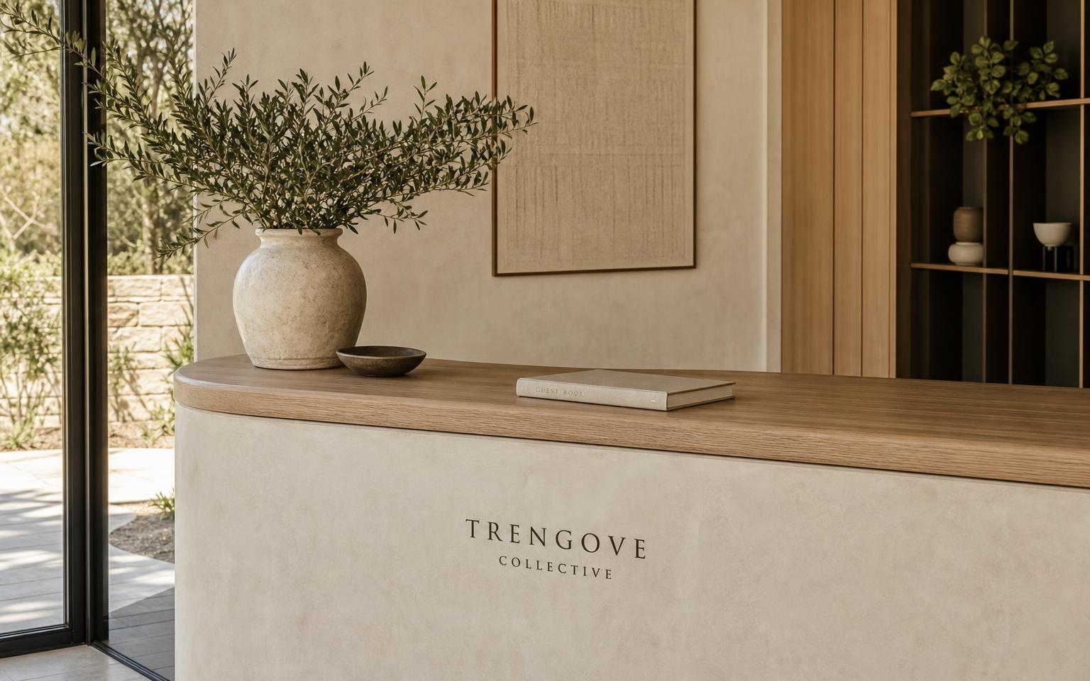 A warm, curved plaster reception desk with a ceramic vessel and soft natural light